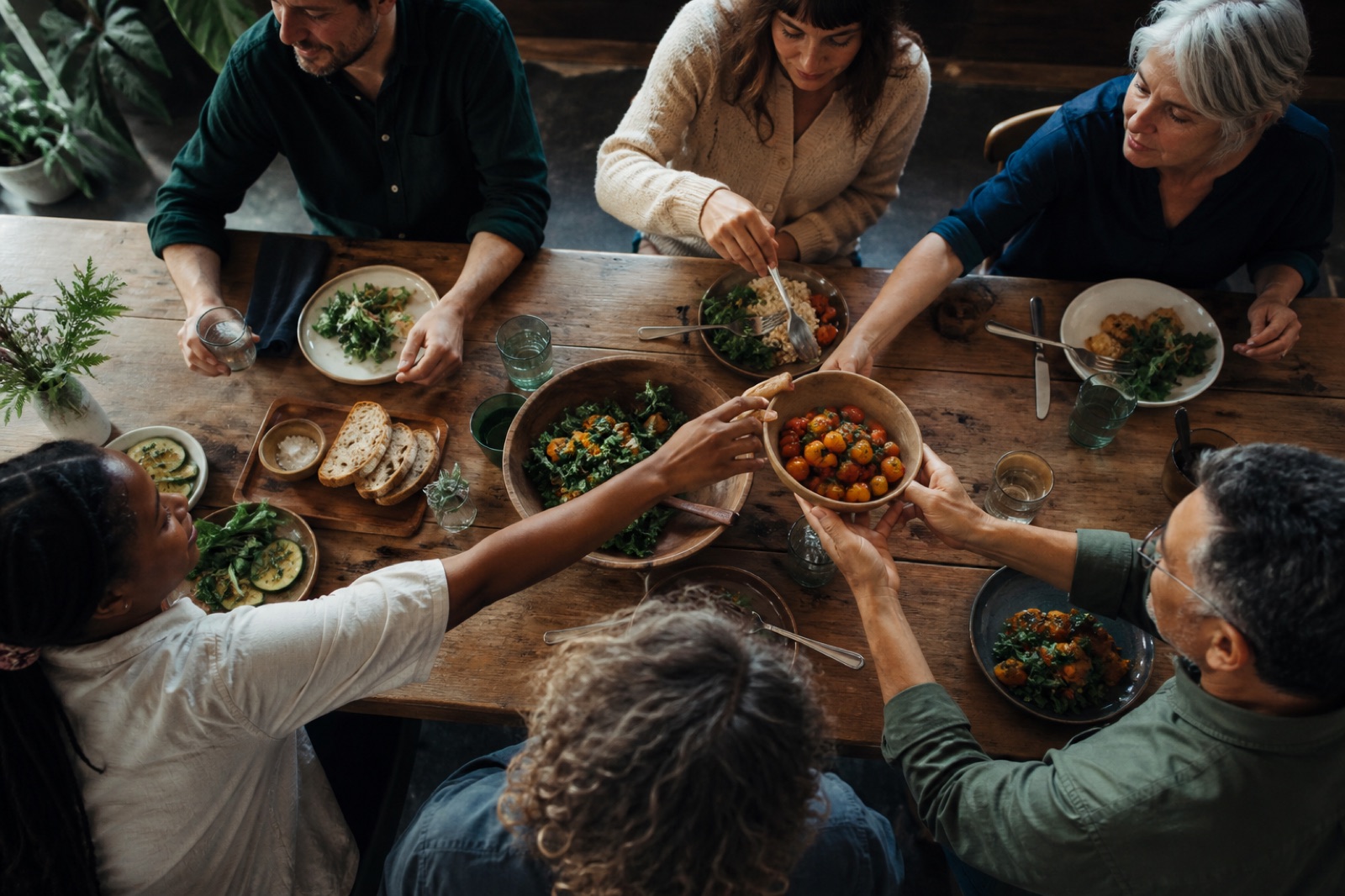 Friends of varied ages sharing a meal around a wooden table